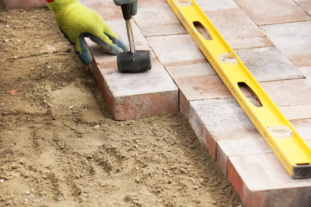 Installing pavers over sand bed.